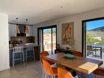 a kitchen and living room with a wooden table and chairs at Villa Ô Bord de Mer avec piscine privée in Conca