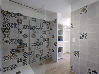 a bathroom with a glass shower with mosaics on the wall at Villa Ô Bord de Mer avec piscine privée in Conca