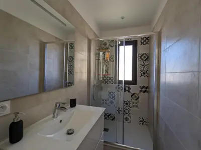 a white bathroom with a shower and a sink at Villa Ô Bord de Mer avec piscine privée in Conca