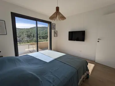 a bedroom with a large bed and a large window at Villa Ô Bord de Mer avec piscine privée in Conca