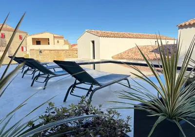 a patio with two chairs and a table and some plants at Villa familiale avec piscine,15 min des plages in Lavatoggio