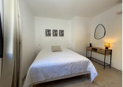 a white bedroom with a bed and a mirror at Villa familiale avec piscine,15 min des plages in Lavatoggio