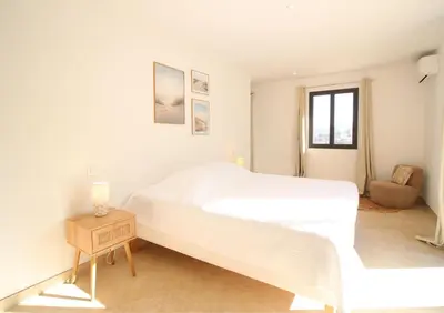 a white bedroom with a large bed and a chair at Villa familiale avec piscine,15 min des plages in Lavatoggio