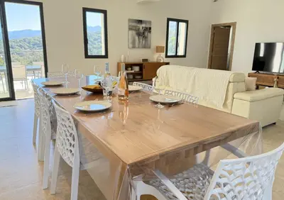 a dining room with a wooden table and chairs at Villa familiale avec piscine,15 min des plages in Lavatoggio