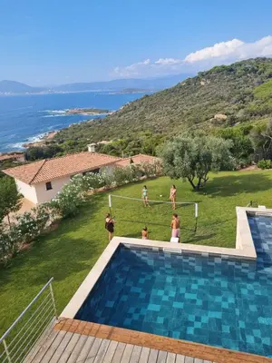 a group of people standing around a swimming pool at Large Family Villa, exceptional sea view in Coti-Chiavari