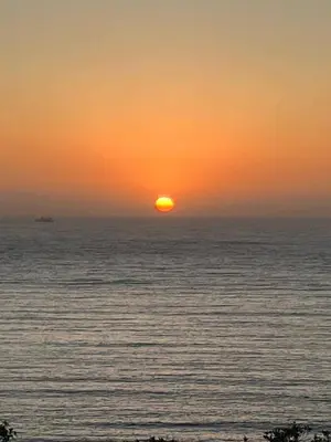 a sunset over the ocean with a ship in the distance at Large Family Villa, exceptional sea view in Coti-Chiavari