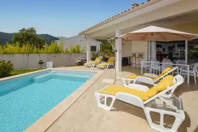 a swimming pool with lounge chairs and an umbrella at Villa Piscine Mer 7 min Vue Montagne Clim in Prunelli-di-Fiumorbo