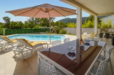 a patio with a table and an umbrella and a pool at Villa Piscine Mer 7 min Vue Montagne Clim in Prunelli-di-Fiumorbo