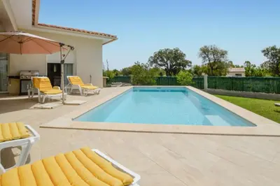 a swimming pool with two chairs and an umbrella at Villa Piscine Mer 7 min Vue Montagne Clim in Prunelli-di-Fiumorbo