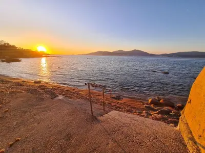 a sunset on the shore of a body of water at Appartement T2 jardin & accès plage privée in Grosseto-Prugna