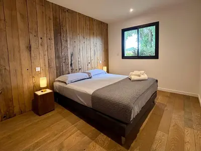 a bedroom with a bed with a wooden wall at Bergerie Sébastien in Zonza