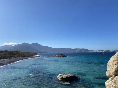 a view of a beach with rocks in the water at Villa Pietralba - Piscine privée & vue montagne - Proche Calvi in Calenzana