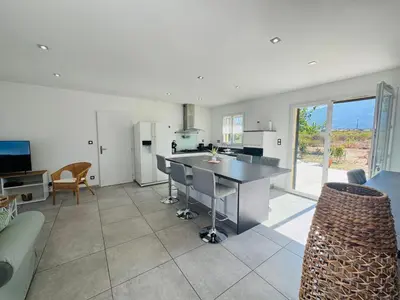 a kitchen and living room with a table and a couch at Villa Pietralba - Piscine privée & vue montagne - Proche Calvi in Calenzana