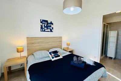 a bedroom with a bed with a blue comforter and two lamps at Mini-villa dans résidence avec piscine T2 BONIFACIO in Bonifacio