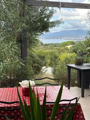 a table and chairs on a patio with a view of the ocean at Famille in Grosseto-Prugna