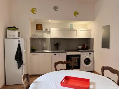 a kitchen with a table and a white refrigerator at Village centre appartement in Calenzana