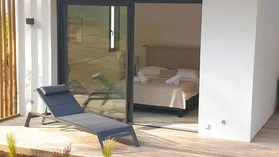 a bedroom with a bed and a chair on a porch at Villa Maria 1. 12 pers, piscine chauffée, 5 min plage in Cirendinu