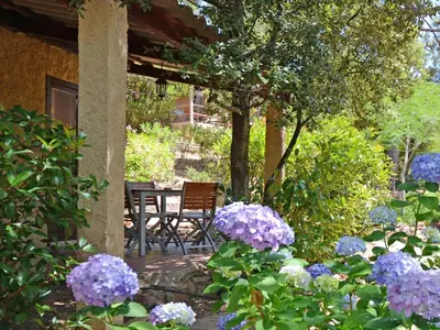 a garden with purple flowers and a table and chairs at Apartment Ruhe und Entspannung inmitten der Macchia by Interhome in Porto-Vecchio