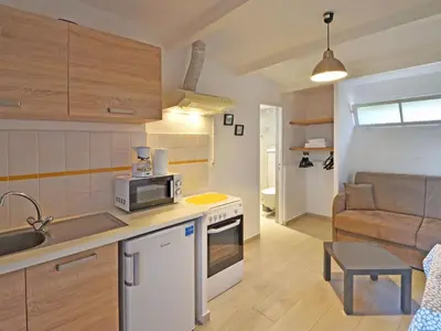 a kitchen and living room with a microwave and a couch at Apartment Ruhe und Entspannung inmitten der Macchia by Interhome in Porto-Vecchio