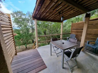 a patio with a table and chairs on a deck at Apartment Ruhe und Entspannung inmitten der Macchia by Interhome in Porto-Vecchio