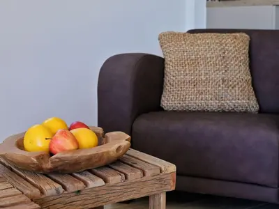 a wooden bowl of fruit on a table next to a couch at Holiday Home Domaine Punta della Guardia Maison A Figa mit Blick auf das Meer by Interhome in Cervione