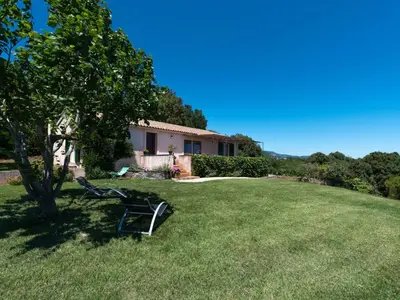 a bench in the grass in front of a house at Holiday Home Weingut Punta della Guardia Ruhig und beschaulich by Interhome in Cervione