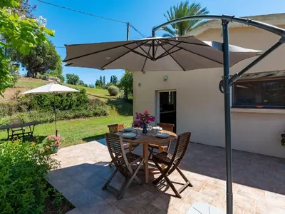 a table and chairs with an umbrella on a patio at Holiday Home Weingut Punta della guardia zwischen Meer und Gebirge by Interhome in Cervione