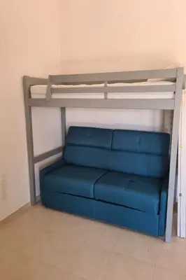 a bunk bed with a blue couch in a room at Holiday Home Casa zinu mit Blick aufs Meer by Interhome in Cargèse