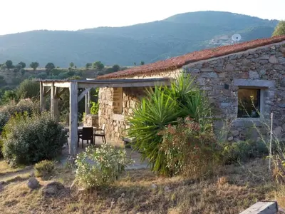 a stone house with a table and a chair outside at Holiday Home in idyllischer Lage im Süden Korsikas by Interhome in Serra-di-Ferro