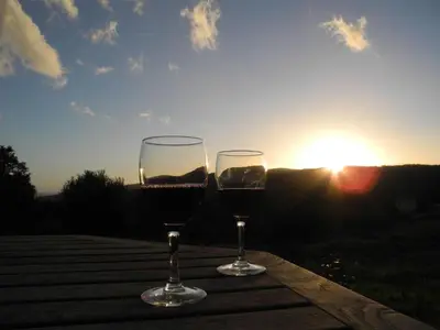 two glasses of wine sitting on a table with the sunset at Holiday Home in idyllischer Lage im Süden Korsikas by Interhome in Serra-di-Ferro