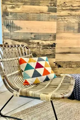 a wicker chair with a pillow and a wooden wall at Holiday Home Luxusvilla aus Stein Concadoro by Interhome in Porto-Vecchio