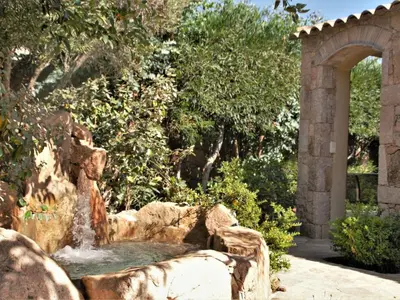 a water fountain in a garden with an arch at Holiday Home Luxuriöse Schäferei 2km vom Strand von Santa Giulia entfernt by Interhome in Porto-Vecchio