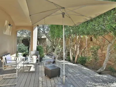 a patio with an umbrella and chairs and a table at Holiday Home Luxuriöse Schäferei 2km vom Strand von Santa Giulia entfernt by Interhome in Porto-Vecchio