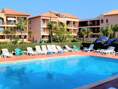 a swimming pool with chairs and umbrellas next to a building at Apartment Blaue Flucht Korsika by Interhome in San-Nicolao