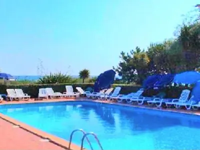 a swimming pool with chairs and umbrellas at Apartment Blaue Flucht Korsika by Interhome in San-Nicolao