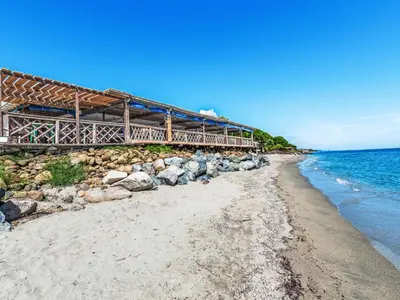 a bridge over a beach with rocks and the ocean at Holiday Home Weingut Punta della Guardia Panorama von Macchia und Meer by Interhome in Cervione