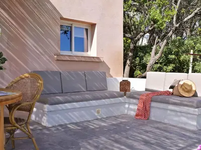 a woman sitting on a couch on a patio at Holiday Home Weingut Punta della Guardia Panorama von Macchia und Meer by Interhome in Cervione