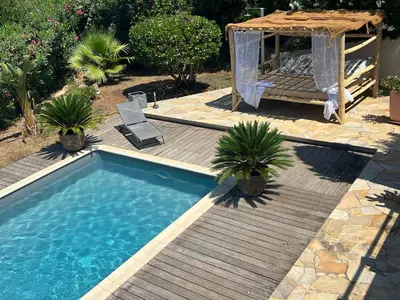 a swimming pool with a wooden deck and a gazebo at Villa Pierretti - Vue mer Panoramique in Coti-Chiavari