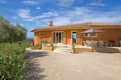 a house with a patio and a table and an umbrella at Villa Pierretti - Vue mer Panoramique in Coti-Chiavari