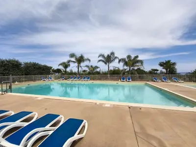 a swimming pool with blue and white chairs and palm trees at Apartment with Garden - Two Pools - Beach Access in Poggio-Mezzana