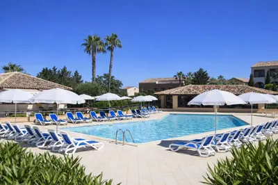 a pool with blue and white chairs and umbrellas at Appartement avec piscines et plage à pied in Linguizzetta