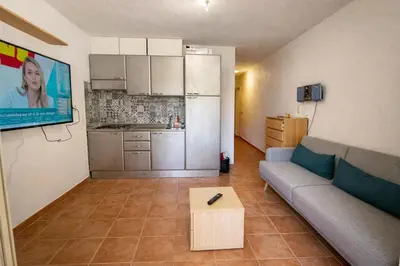 a living room with a couch and a kitchen at Appartement avec piscines et plage à pied in Linguizzetta
