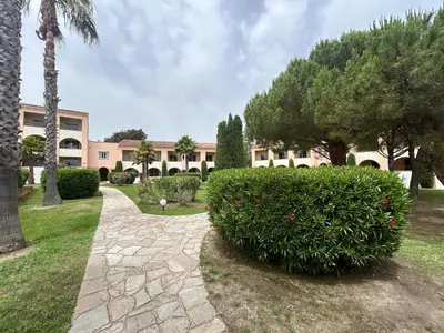 a garden with a large bush in front of a building at Appartement avec piscines et plage à pied in Linguizzetta
