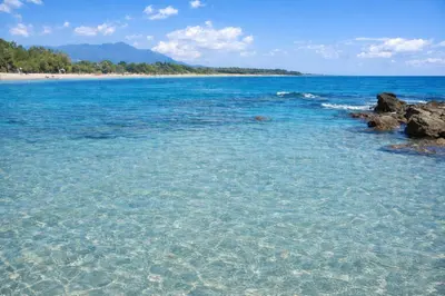 a beach with clear blue water and rocks at Appartement avec piscines et plage à pied in Linguizzetta