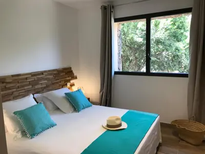 a bedroom with a bed with a hat on it at Les Bergeries de Porra in Porto-Vecchio