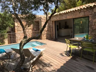 a deck with a table and chairs next to a pool at Les Bergeries de Porra in Porto-Vecchio