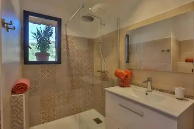 a bathroom with a sink and a shower with a window at Les Bergeries de Porra in Porto-Vecchio
