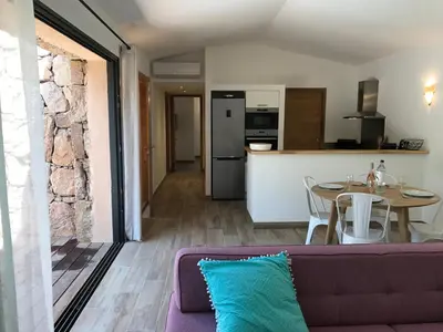 a living room with a couch and a table and a kitchen at Les Bergeries de Porra in Porto-Vecchio