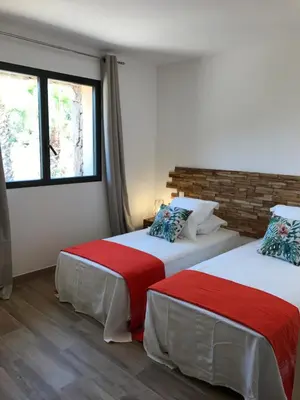 two beds in a room with two windows at Les Bergeries de Porra in Porto-Vecchio