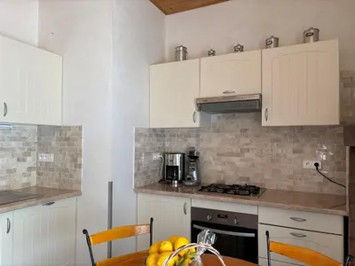a kitchen with white cabinets and a table with fruit at Maison de caractère CASA LECA, piscine privée chauffée in Feliceto